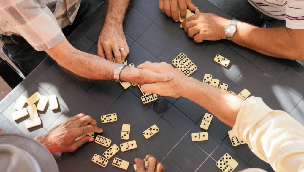 A handshake over a dominoes game at a boardgames table