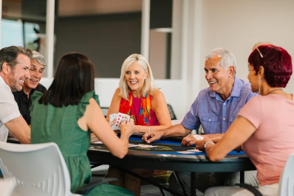 A group of couples sitting and playing cards in the game room of a manufactured home